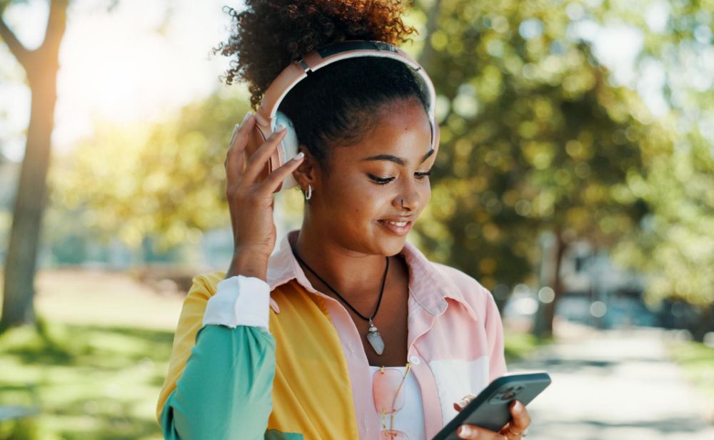 Person listening to music on headphones while using a smartphone